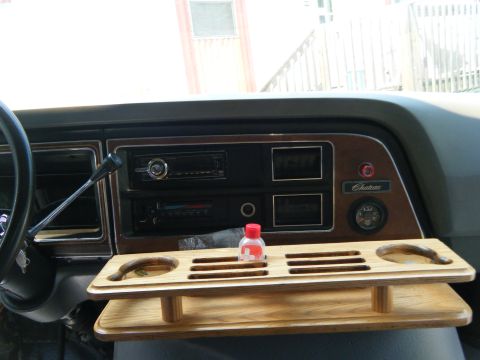 1988 Ford E350 - The interior of a 1988 Ford E350 Chateau van shows its dashboard with a wooden tray and a bottle.