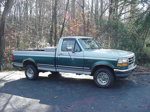 1979 Ford Bronco - This two-tone Ford F-150 pickup truck is parked on a paved surface with a wooded area behind it.