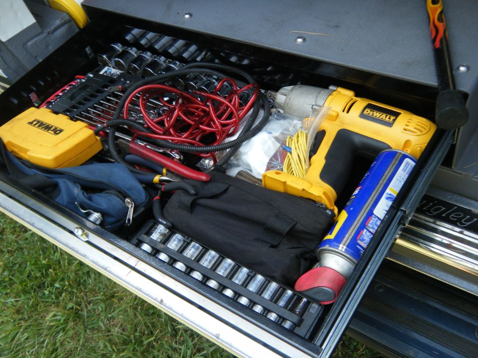 Open toolbox drawer filled with various tools including a yellow DeWalt impact wrench, sockets, pliers, and a can of lubricant