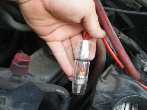 1988 Ford E350 - Close-up of a hand holding an in-line fuse holder with red wiring in an engine bay.