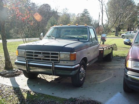 1979 Ford Bronco - A two-tone Ford F-Series truck with a flatbed is parked on a concrete surface.