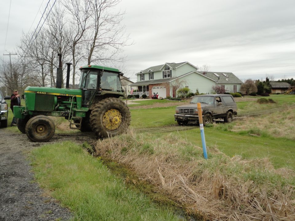 Dark gray 1995 Ford Bronco driving on a muddy field
