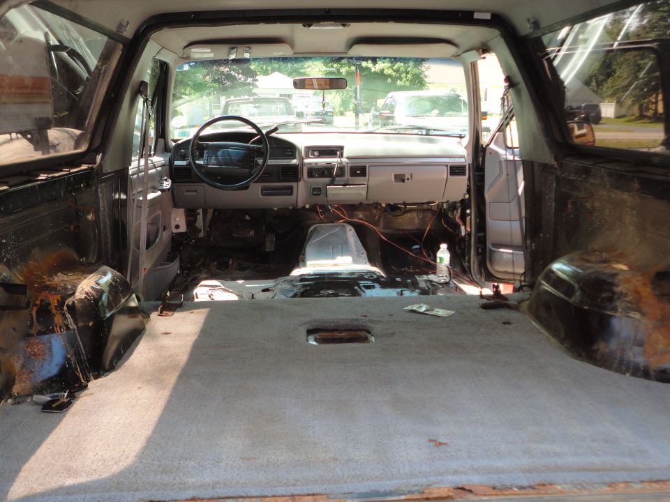 Interior of a 1995 Ford Bronco with seats removed and dashboard partially disassembled
