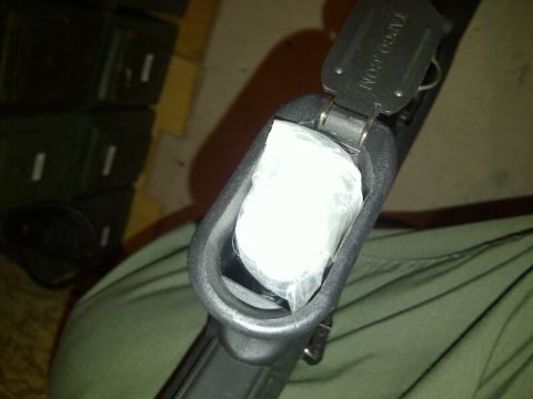 1989 Ford Bronco - A close-up view of a gun's magazine well containing a white plastic bag, with visible text on the latch and a website watermark.