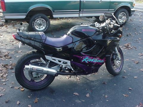 1979 Ford Bronco - A black sportbike motorcycle with purple accents is parked next to a green pickup truck.