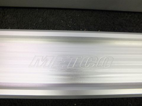2003 Ford Crown Victoria - Close-up of a machined aluminum control arm bearing an engraved METCO brand mark.