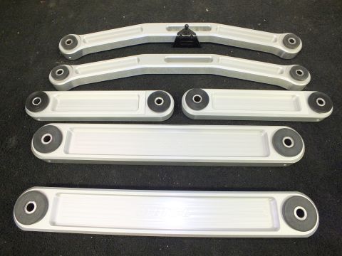 2003 Ford Crown Victoria - Six machined aluminum control arms with bushings arranged in a row on carpet.