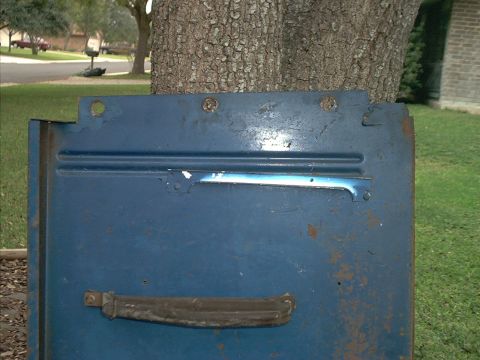 1971 Ford Bronco - A close-up of a blue vehicle door, showing its weathered surface and a Supermotors watermark.
