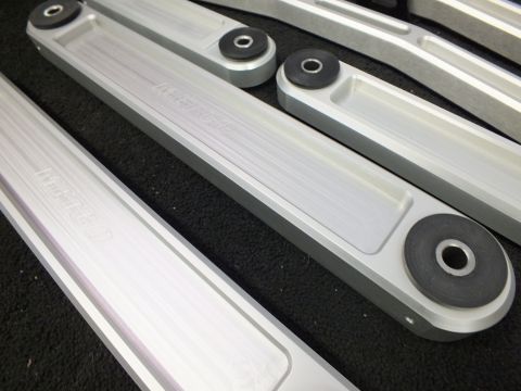 2003 Ford Crown Victoria - Multiple machined aluminum suspension links laid out, faint METCO engraving visible.