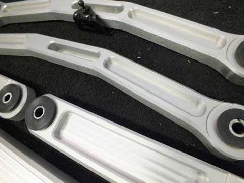 2003 Ford Crown Victoria - Several billet aluminum suspension links with pressed bushings shown side by side.