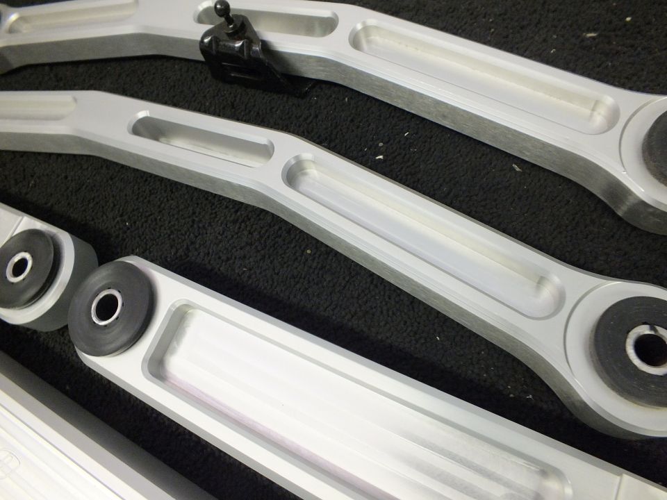 Machined aluminum control arms with bushings and end-link bolt on black foam