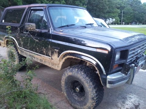 1986 Ford Bronco - This 1986 Ford Bronco is heavily covered in mud, suggesting it has been used off-road.