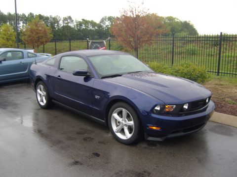 2007 Ford Mustang - A blue Ford Mustang GT is parked outside on a wet day, with another blue car visible to the left.