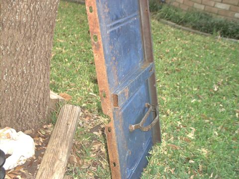 1971 Ford Bronco - A blue door, likely from an older vehicle, rests against a tree in a grassy area.