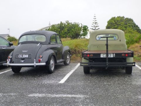 1969 Lincoln Continental - Two older vehicles, a Morris Minor and a flatbed truck, are parked next to each other in a lot.