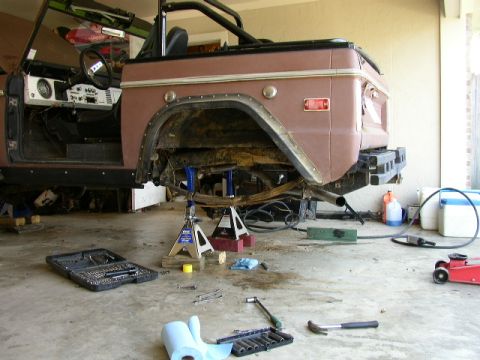 1995 Ford Bronco - A brown 1978 Ford Bronco is shown on jack stands in a garage, undergoing repairs with tools scattered around.