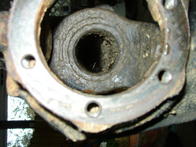 Rusted metal part with a circular opening and bolt holes