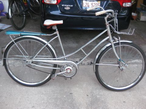 1994 Ford Bronco - A vintage bicycle with chrome accents and a white seat is parked in front of a car.