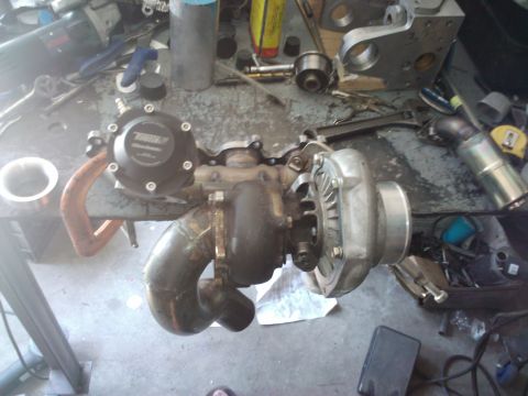 1995 Ford Probe - A turbocharger assembly with a black wastegate is shown on a workbench with various tools and parts.