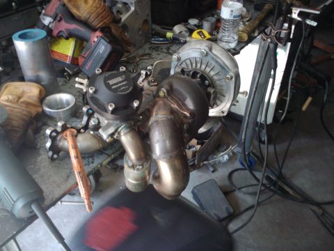 1995 Ford Probe - A turbocharger and wastegate assembly sits on a cluttered workbench, surrounded by tools and parts.
