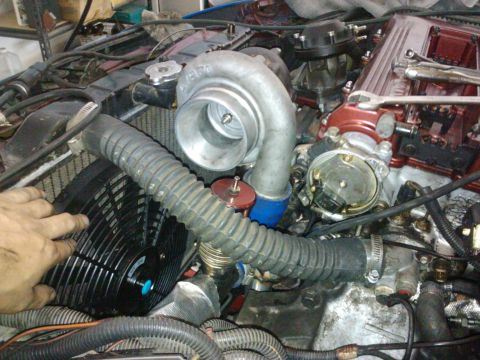 1995 Ford Probe - Close-up view of engine components, including a turbocharger and fan, during installation or maintenance.