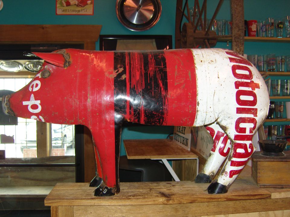 Red and white metal pig sculpture with black stripes and text reading 'Pepsi' and 'Motorola'