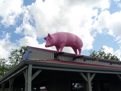 2007 Ford Mustang - Large pink pig sculpture sits atop a building's roof under a partly cloudy sky.