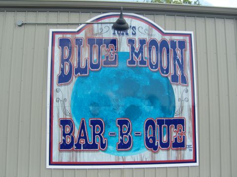 2007 Ford Mustang - A sign for a barbecue restaurant hangs on a metal-sided building.