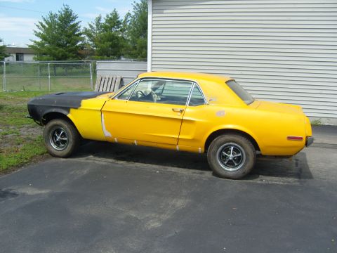 2007 Ford Mustang - This classic car, likely a 1967 Mustang, is in a state of repair with a primer-covered hood and bodywork.