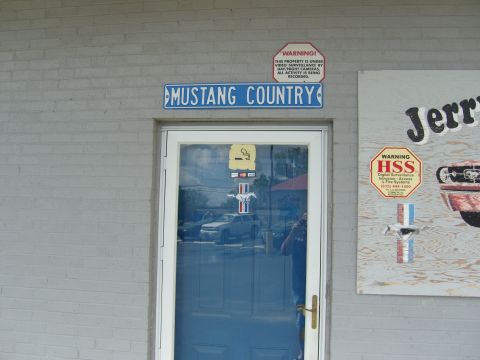 2007 Ford Mustang - A building entrance features a "Mustang Country" sign and reflections of vehicles in the glass door.