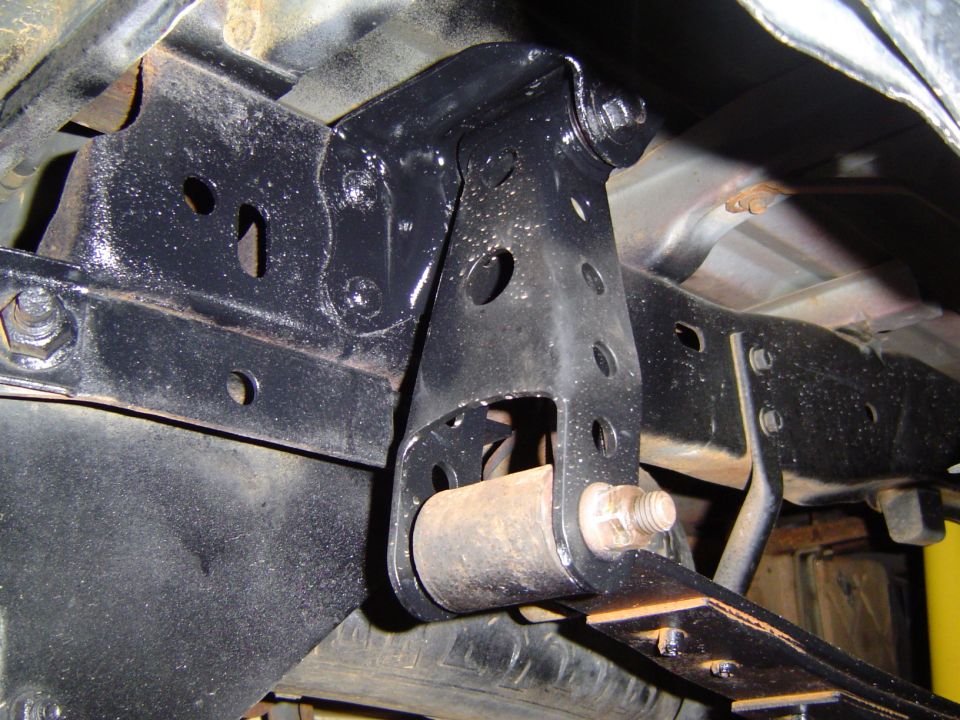 Close-up of a black painted truck suspension bracket with a bolt and bushing