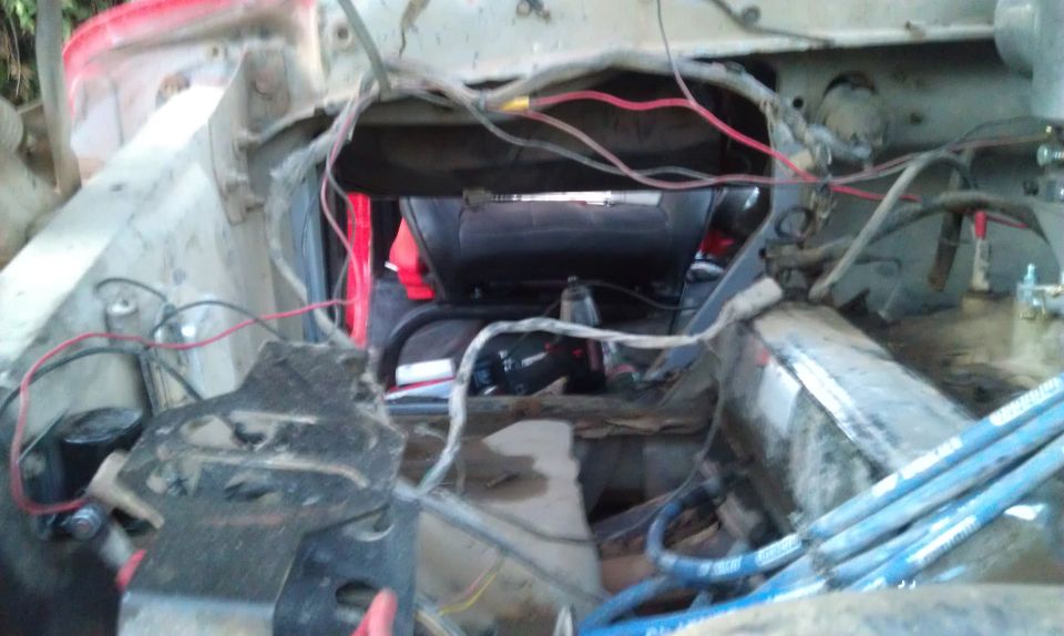 view into vehicle engine bay with exposed wires and parts
