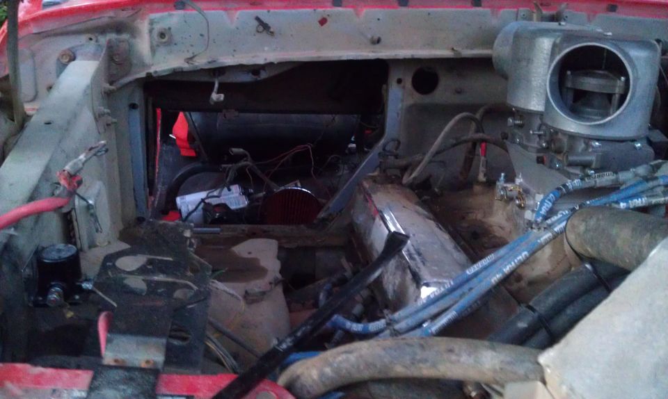Engine bay with red paint, exposed wires, and a large carburetor