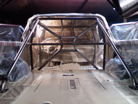 1989 Ford Bronco - The interior of a vehicle is covered in protective sheeting, with a newly installed roll cage visible.