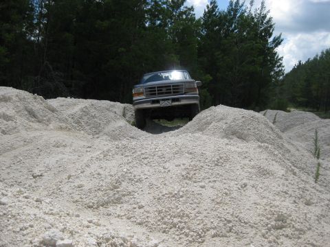 1994 Ford Bronco - A 1994 Ford Bronco navigates a challenging terrain of white gravel mounds.