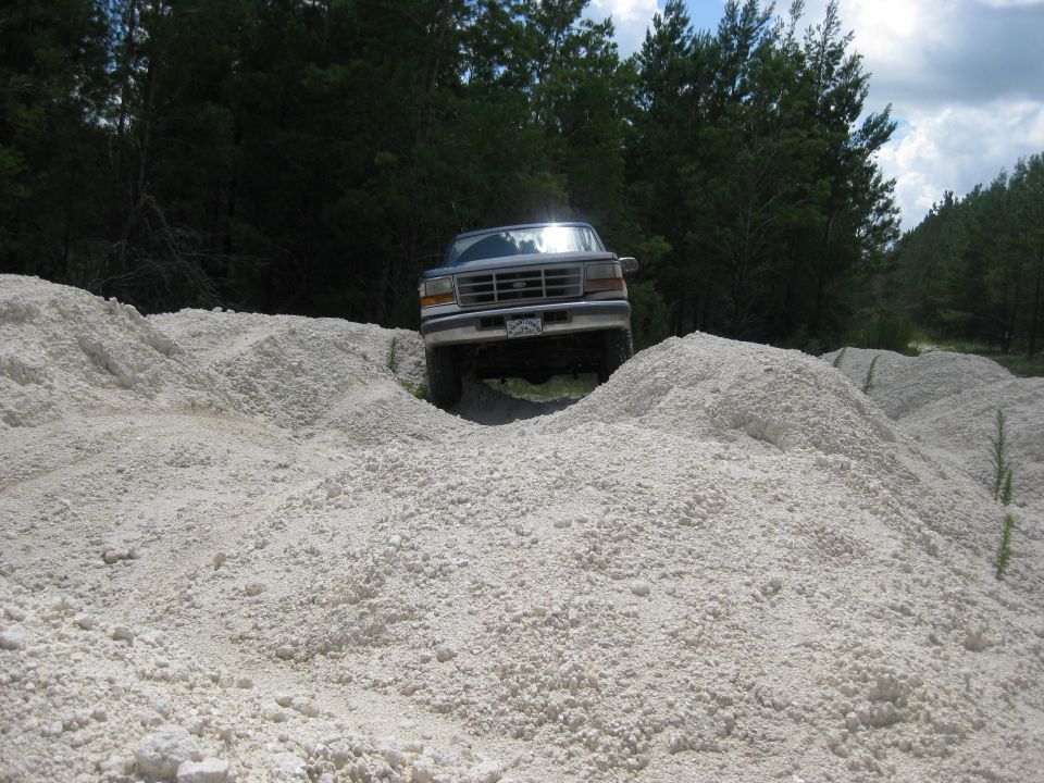 1994 Ford Bronco driving over white gravel piles