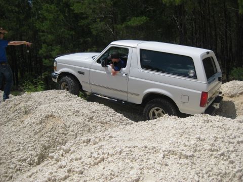 1994 Ford Bronco - A white Ford Bronco navigates a rocky terrain with a person pointing in the background.
