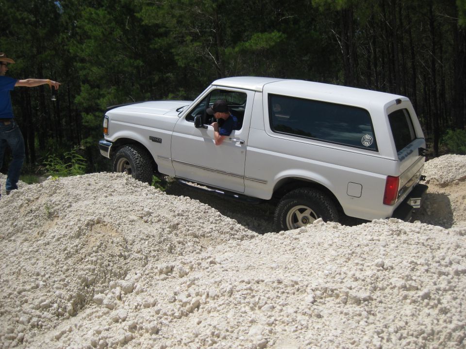 White Ford Bronco driving over a pile of light-colored rocks