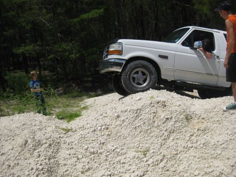 1994 Ford Bronco - White 1994 Ford Bronco climbing a dirt mound with two people nearby.