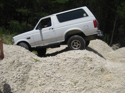 1994 Ford Bronco - A white 1992 Ford Bronco navigates a challenging off-road terrain.