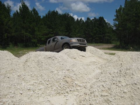1994 Ford Bronco - A gray pickup truck navigates a dirt mound, appearing to be a 1997 model.