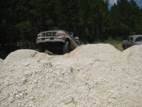 1994 Ford Bronco - 1994 Ford Bronco navigates a challenging off-road terrain of dirt mounds.