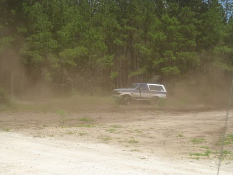1994 Ford Bronco - A two-tone Ford Bronco is seen driving off-road, creating a cloud of dust.
