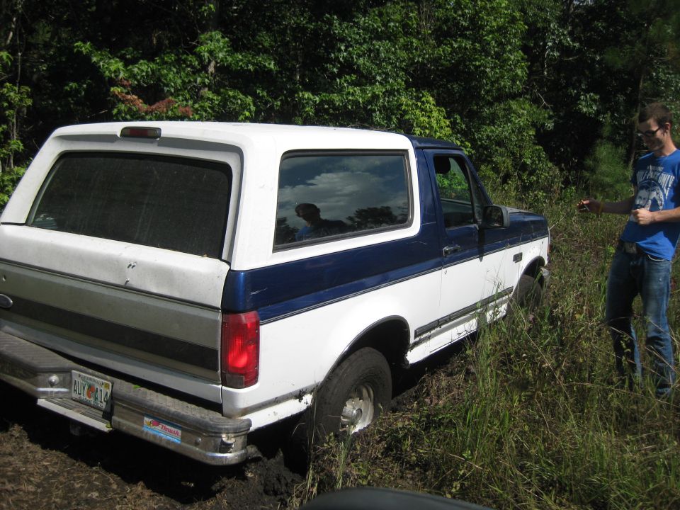 1994 Ford Bronco stuck in mud with a person standing nearby