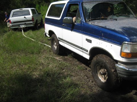 1994 Ford Bronco - Two Ford Broncos are stuck in the mud, with one vehicle attempting to tow the other out.