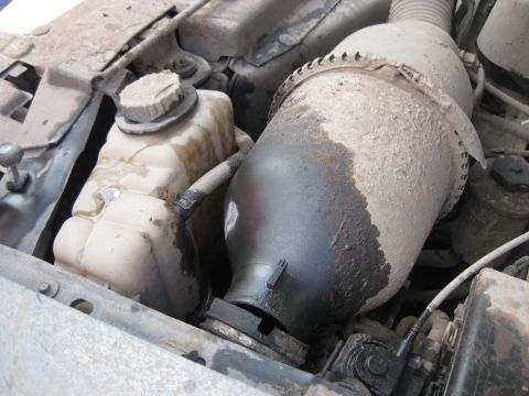 1994 Ford Bronco - Close-up of engine bay components, including coolant reservoir and air intake, showing wear and dust.