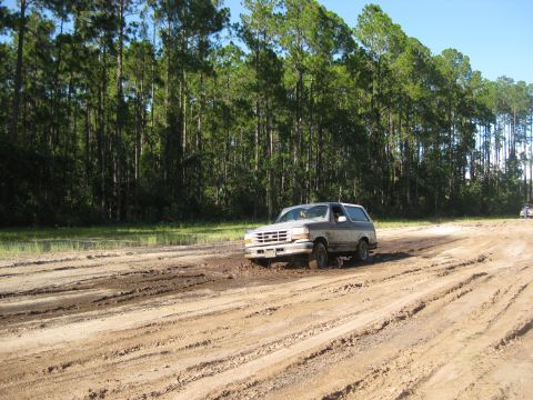 1994 Ford Bronco - A Ford Bronco navigates a muddy track, kicking up dirt as it goes.