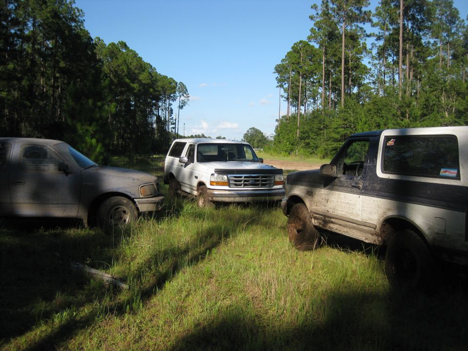 1994 Ford Bronco front grille and side view, parked with two other SUVs in a grassy area