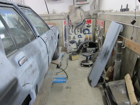 1991 Ford LTD Crown Victoria - A car in a workshop setting, surrounded by tools and car parts, appears to be undergoing some form of repair or restoration.