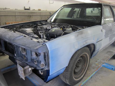 1991 Ford LTD Crown Victoria - This Ford Crown Victoria is in a workshop, likely for repairs or customization, with its hood up revealing the engine bay.
